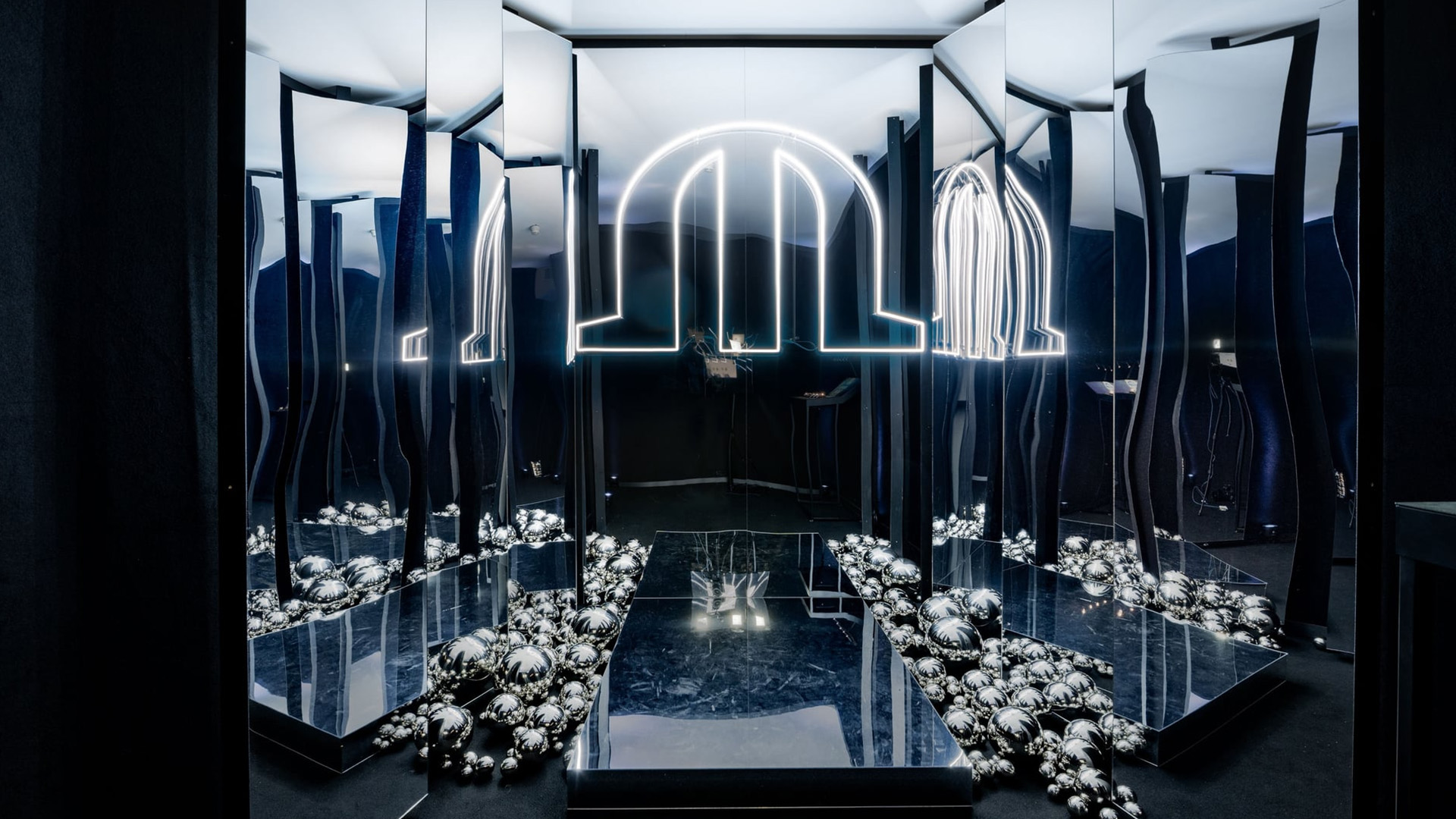 Spiegelinstallation mit leuchtendem Bogenmotiv und verspiegelten Kugeln in einem immersiven Ausstellungsraum.