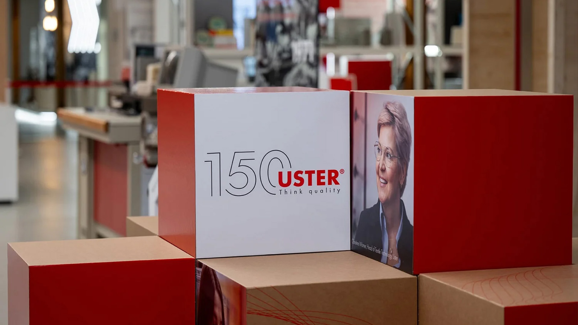 Markeninszenierung mit roten und weissen Kuben in einer Produktionsumgebung, gestaltet zum 150-jährigen Jubiläum von Uster Technologies.