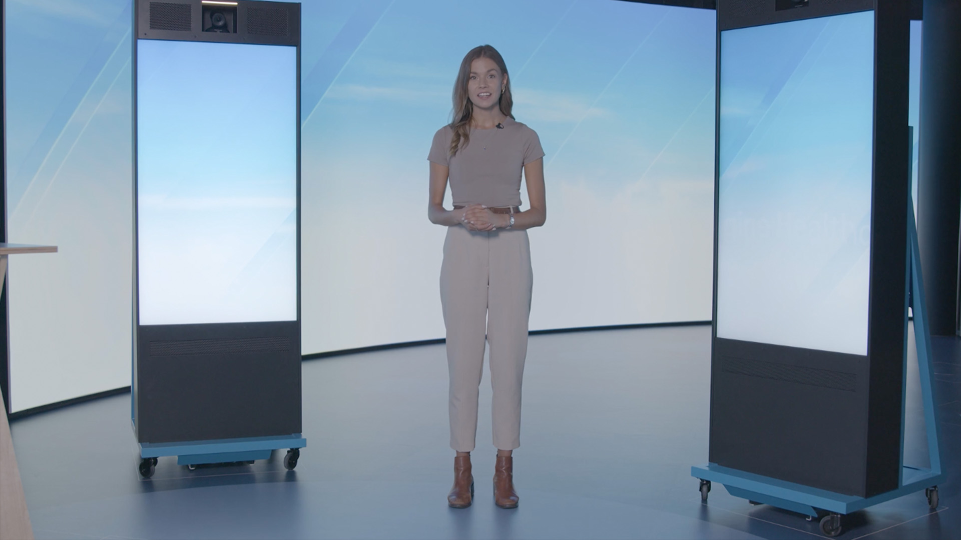 Moderatorin präsentiert in einem modernen Studio zwischen digitalen Displays während einer virtuellen Veranstaltung.