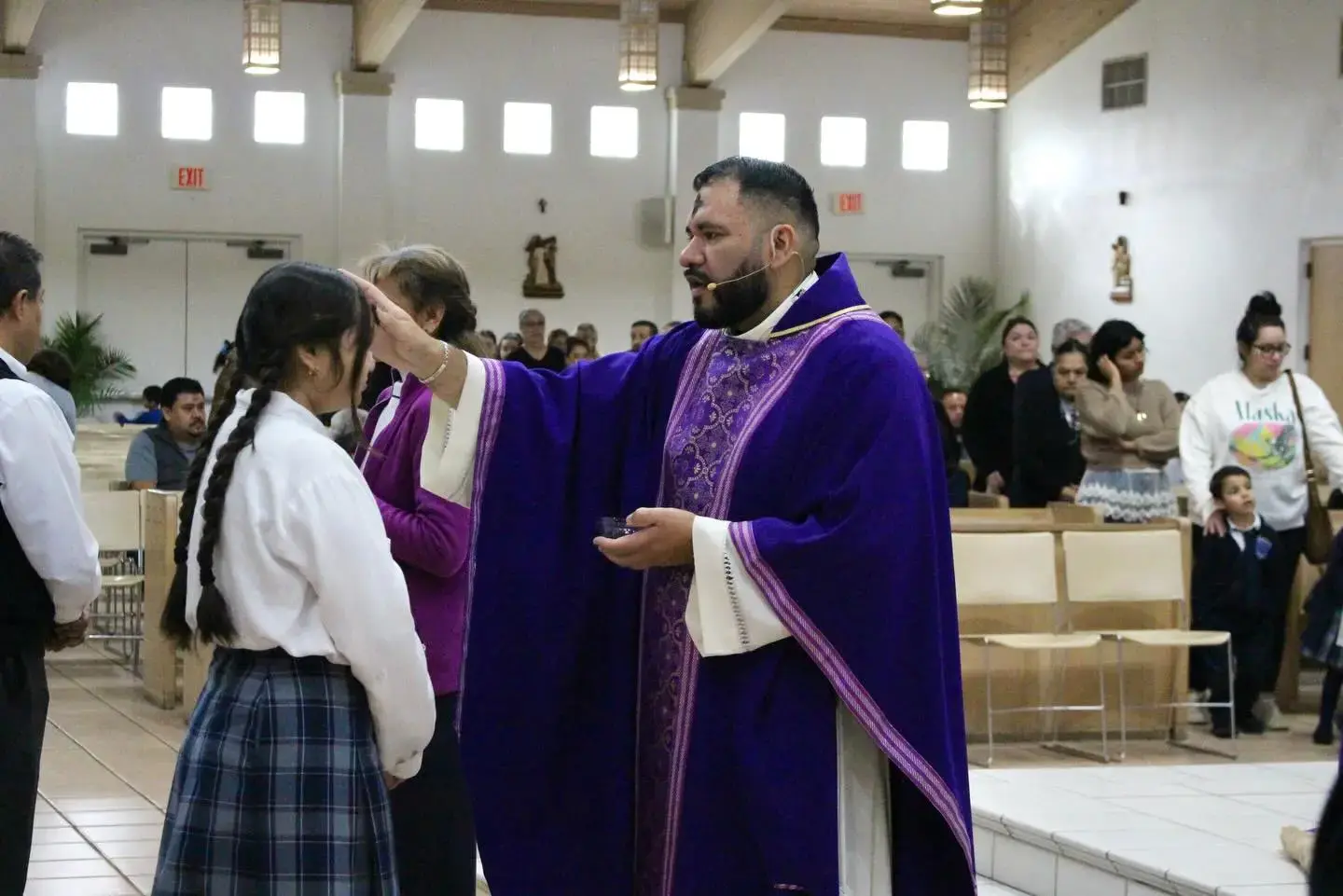 Priest placing ashes on student's forehead during Ash Wednesday Mass