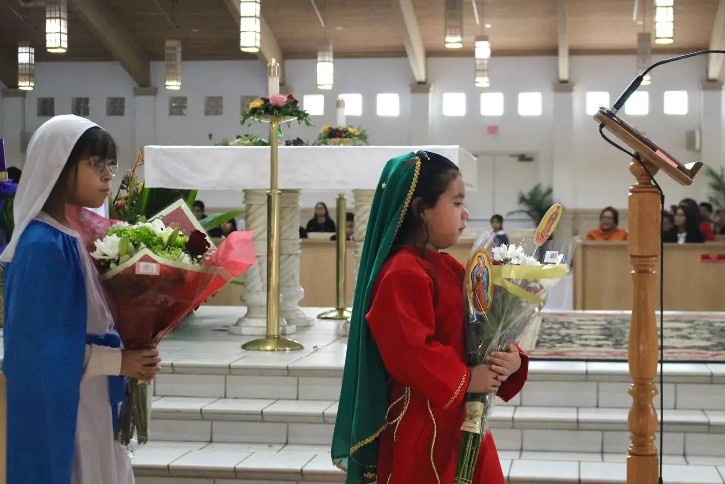 Students in costume carrying flowers during a church ceremony