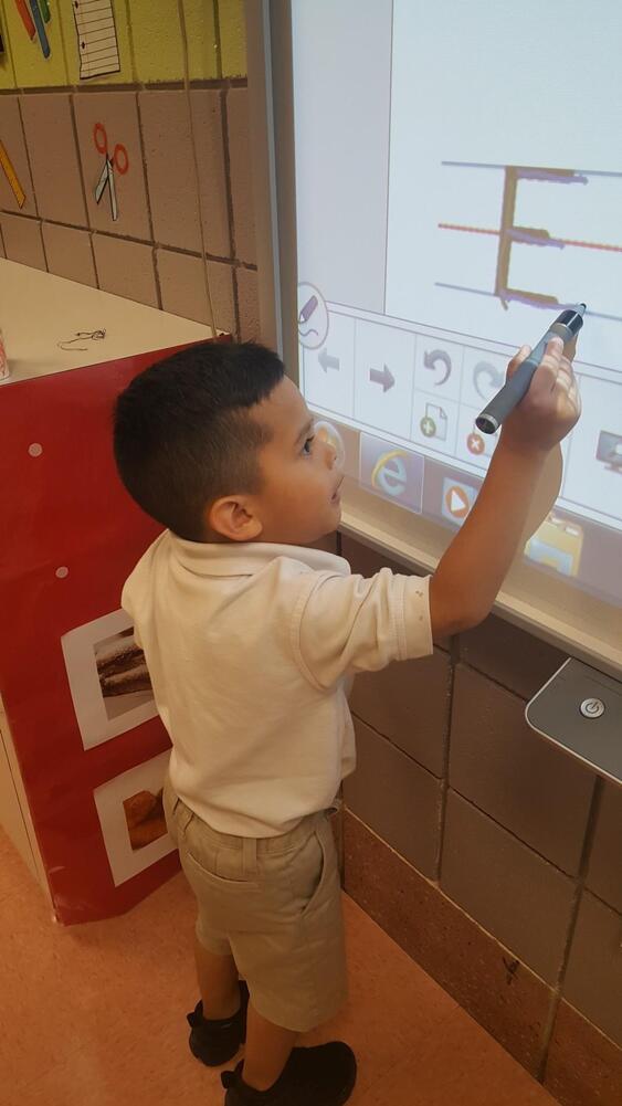 Young student using a stylus pen on an interactive whiteboard