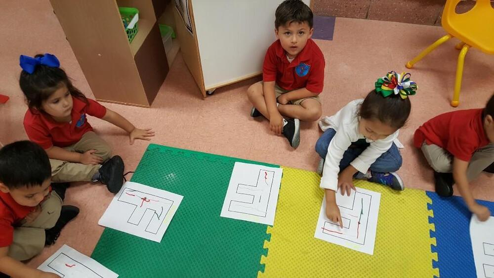 Young students sitting on floor completing maze worksheets together