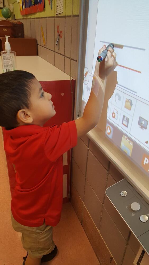 Young student writing on interactive whiteboard in classroom