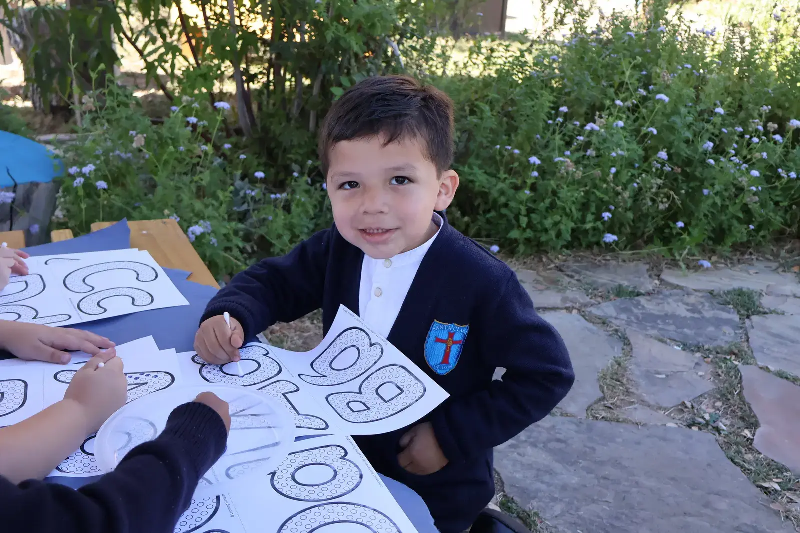 Young student in school uniform tracing alphabet letters outdoors