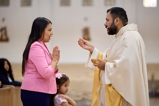 Priest offering communion to woman and child during Mass