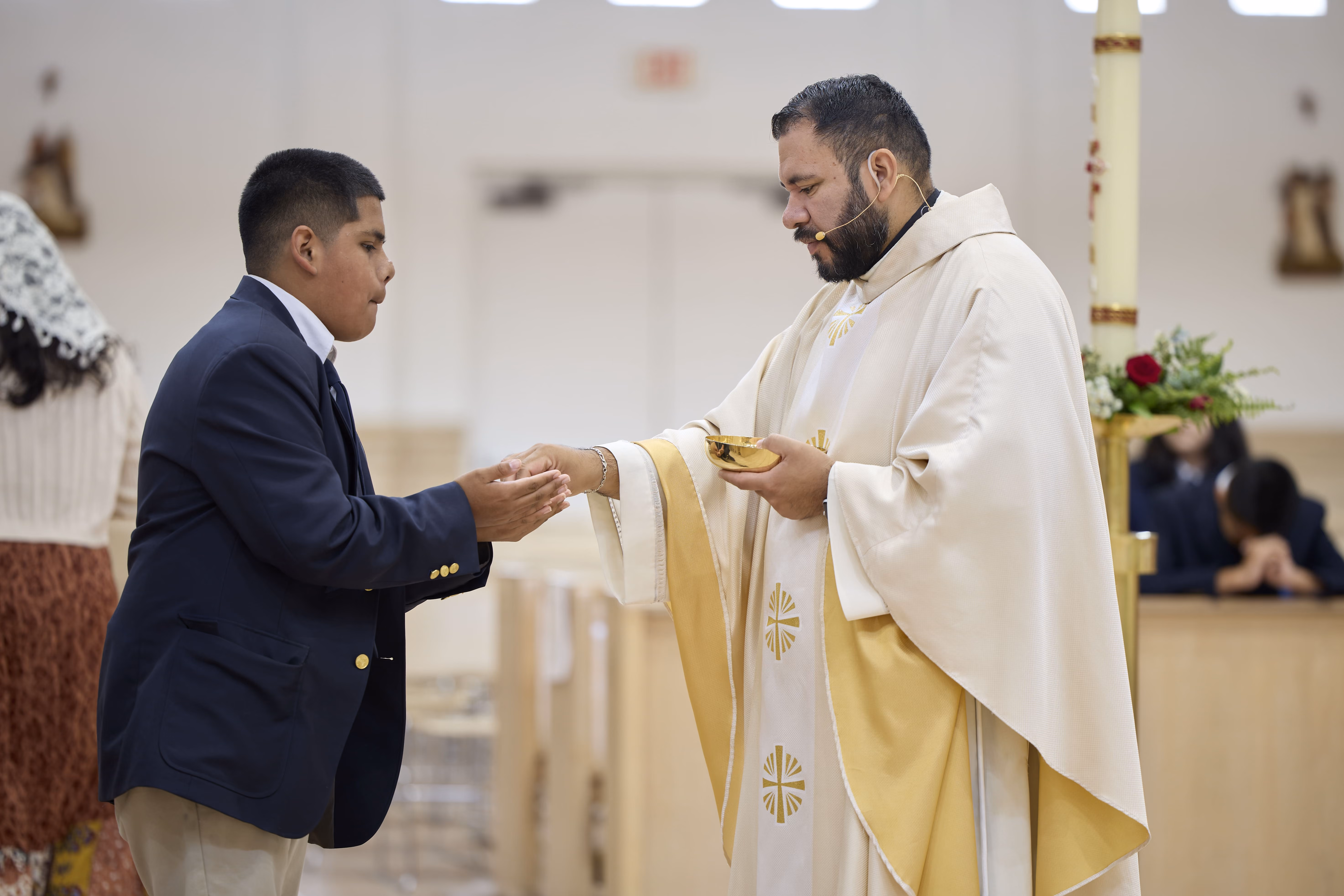 Priest distributing communion to a student during school Mass