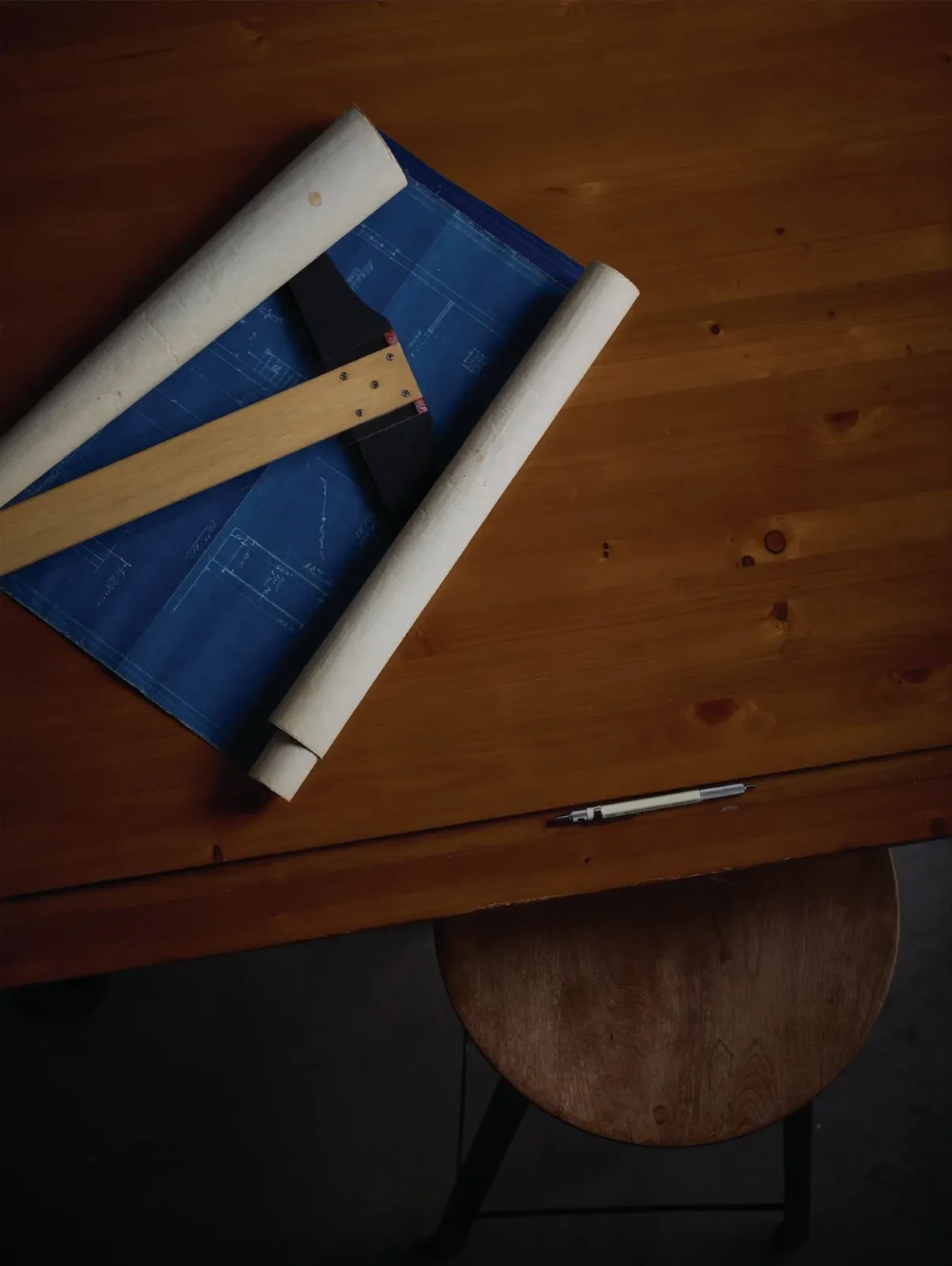 Architectural blueprints and a measuring tool on a desk, representing a structured plan to sales infrastructure.