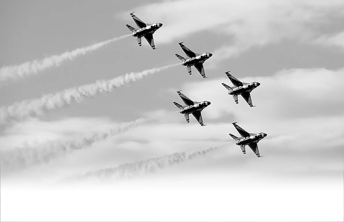 A squadron of jets flying in a precise, unified V-formation through the sky, symbolizing synchronized commercial alignment and strategic order.