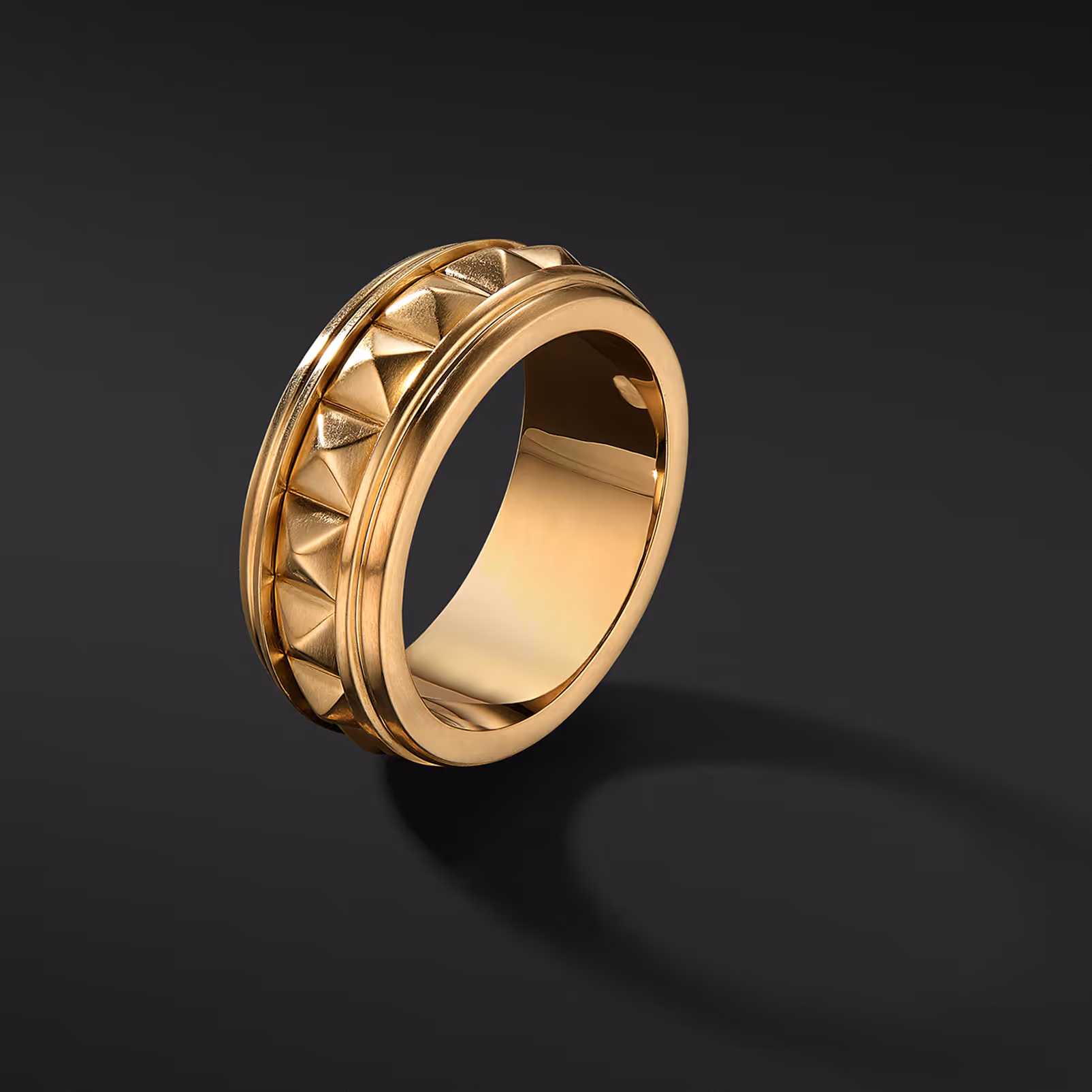 Gold ring with a geometric openwork band on a dark background