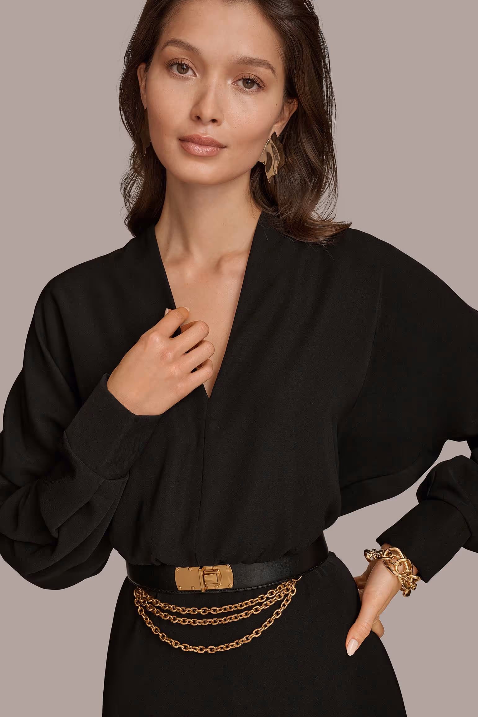 Model wearing a black blouse with a gold-chain belt
