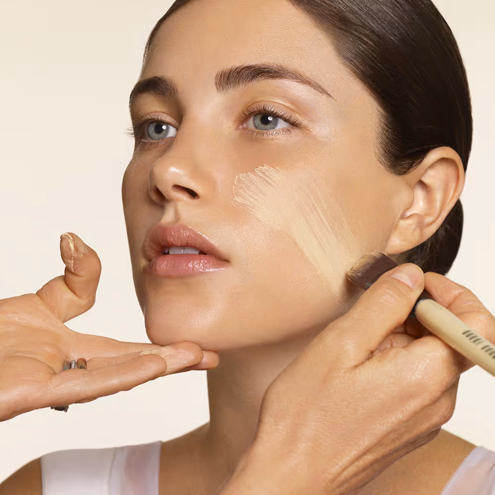 Makeup being applied to a woman's cheek with a brush