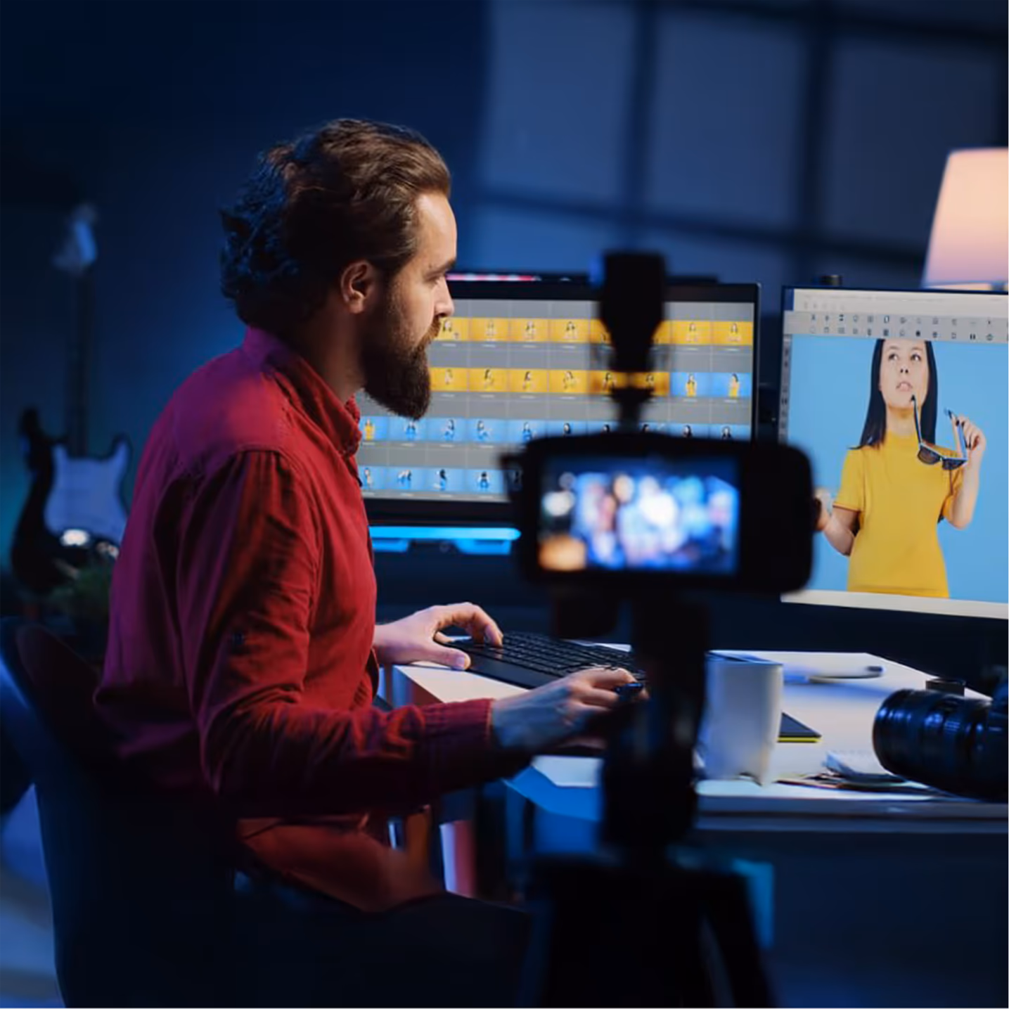 Editor working at multiple monitors in a dimly lit production studio