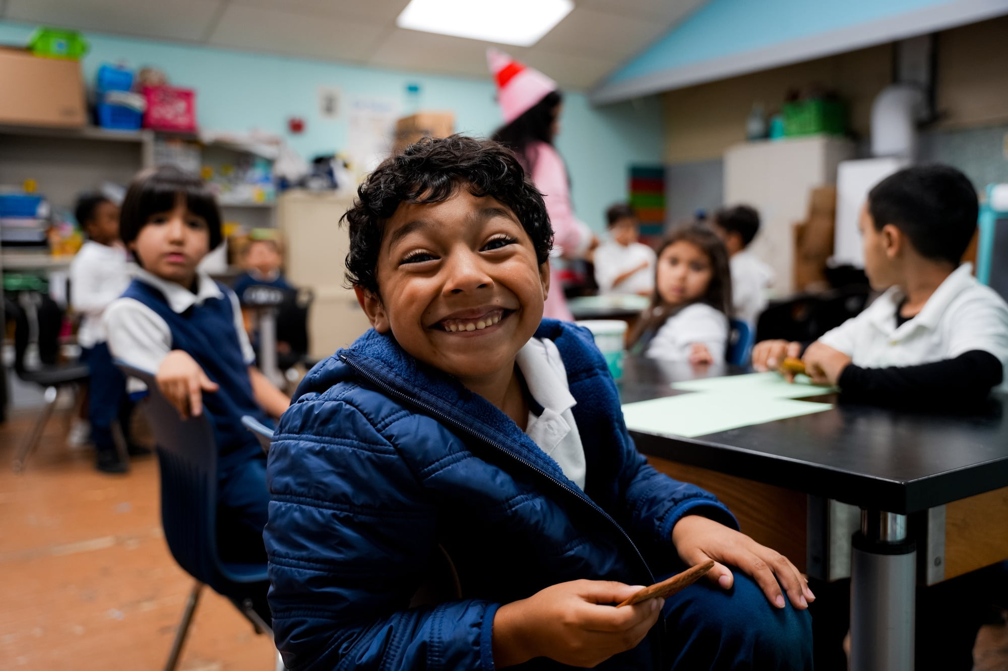 Smiling young student in uniform seated at classroom desk