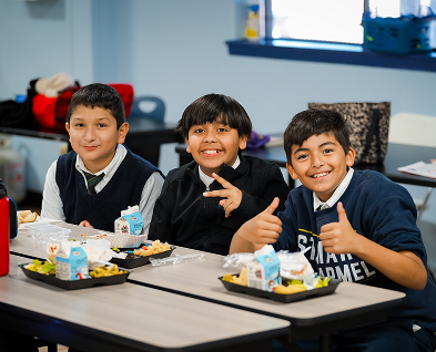 Three male students smiling together during school lunch