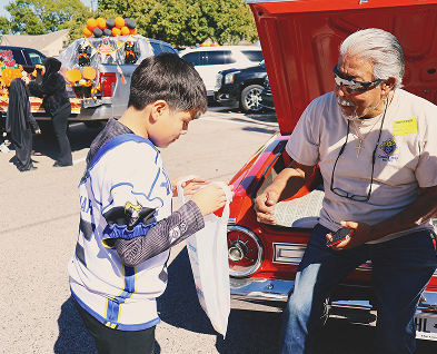 Student receives sticker from adult volunteer at outdoor school event