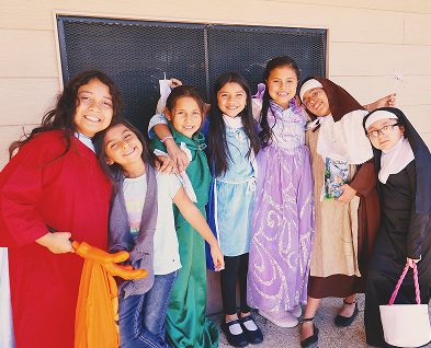 Students in saint costumes posing together at All Saints Day celebration