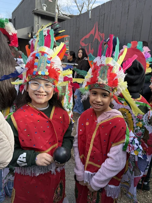 Two students in colorful traditional Aztec dance costumes at cultural event