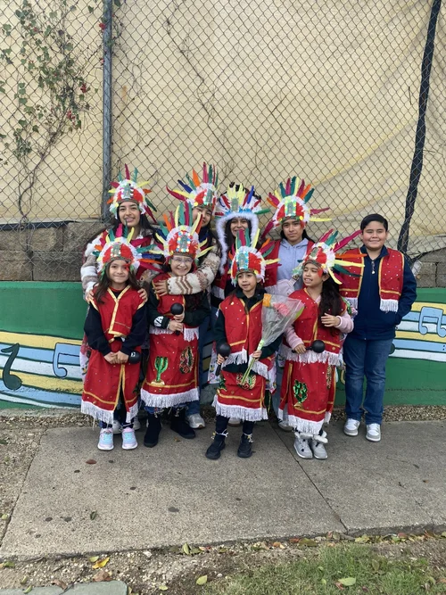 Students in traditional Indigenous regalia posing together outdoors