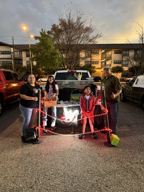 Family posing at trunk or treat event with Halloween decorations