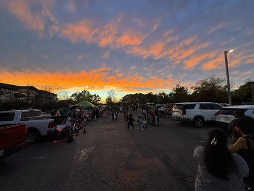 Families gathering in school parking lot at sunset during outdoor event