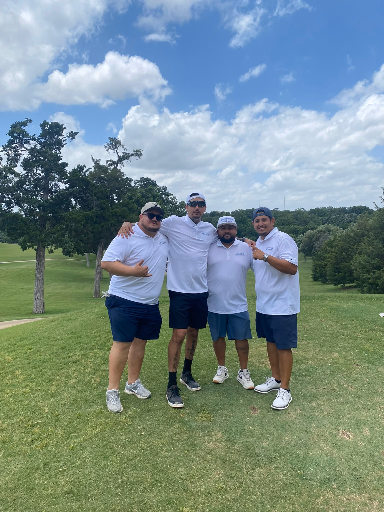 Four team members posing together on a golf course fairway