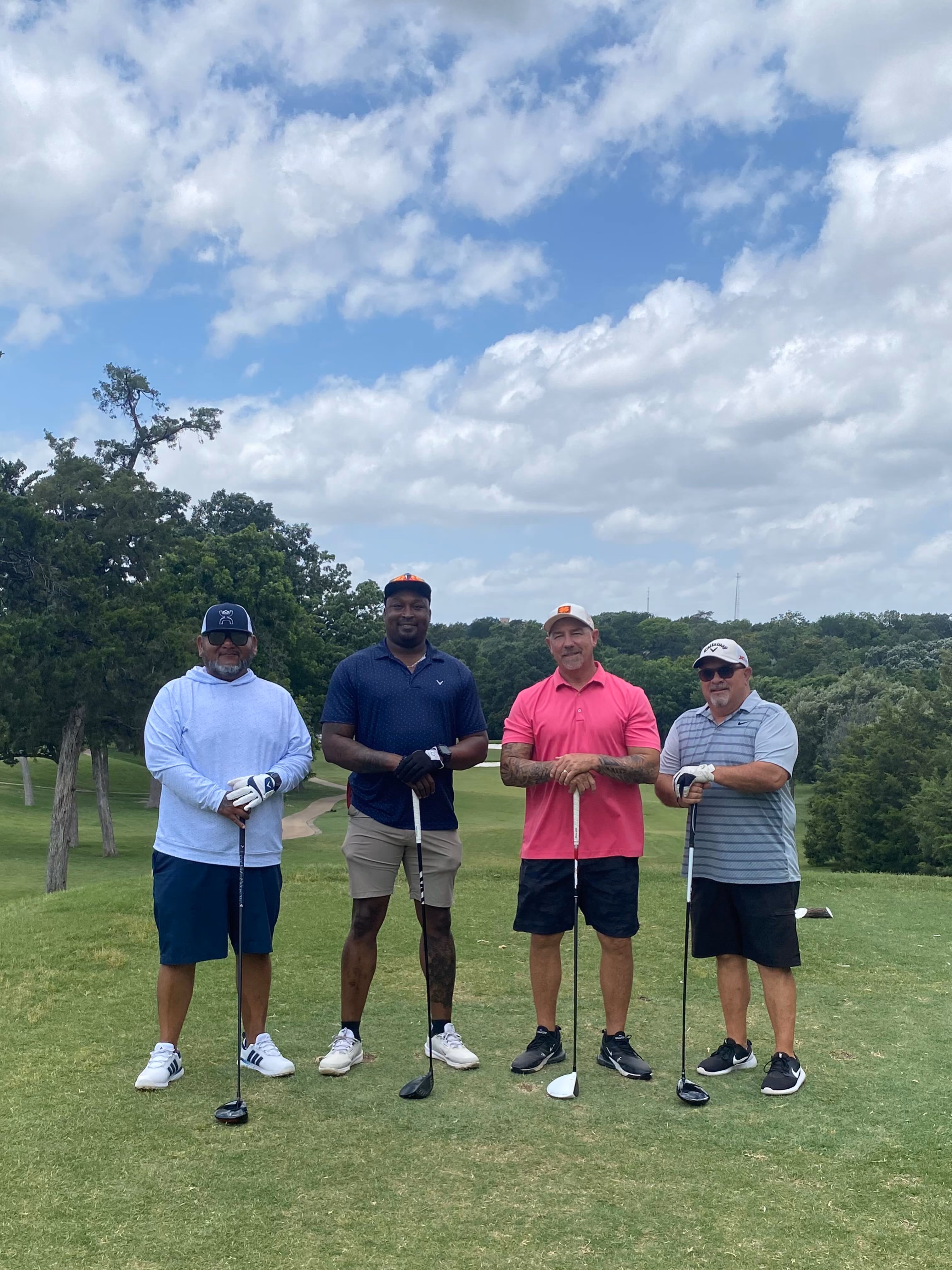 Four golfers posing together on a sunny golf course