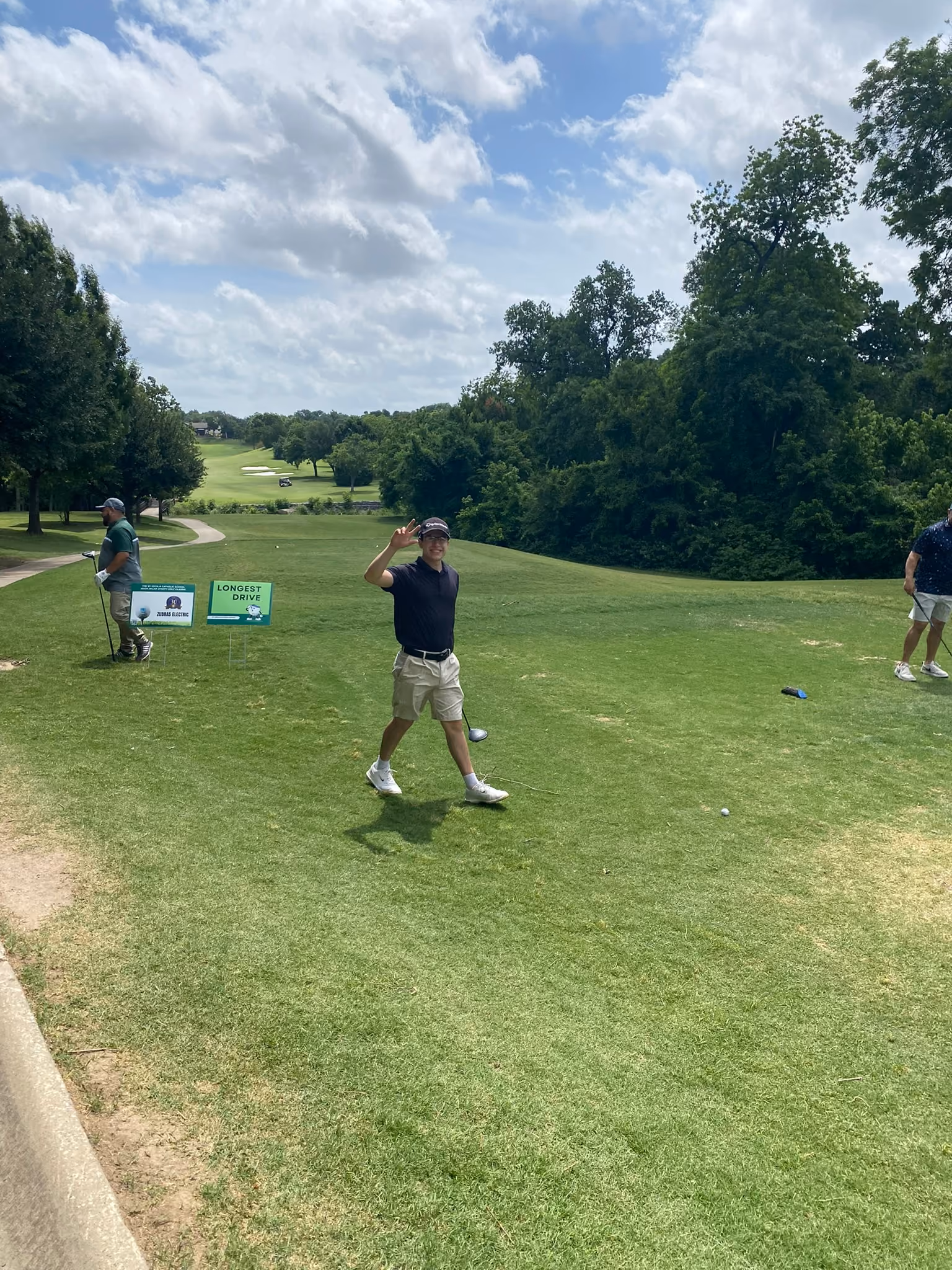 Golfer waving near longest drive sign at charity golf tournament