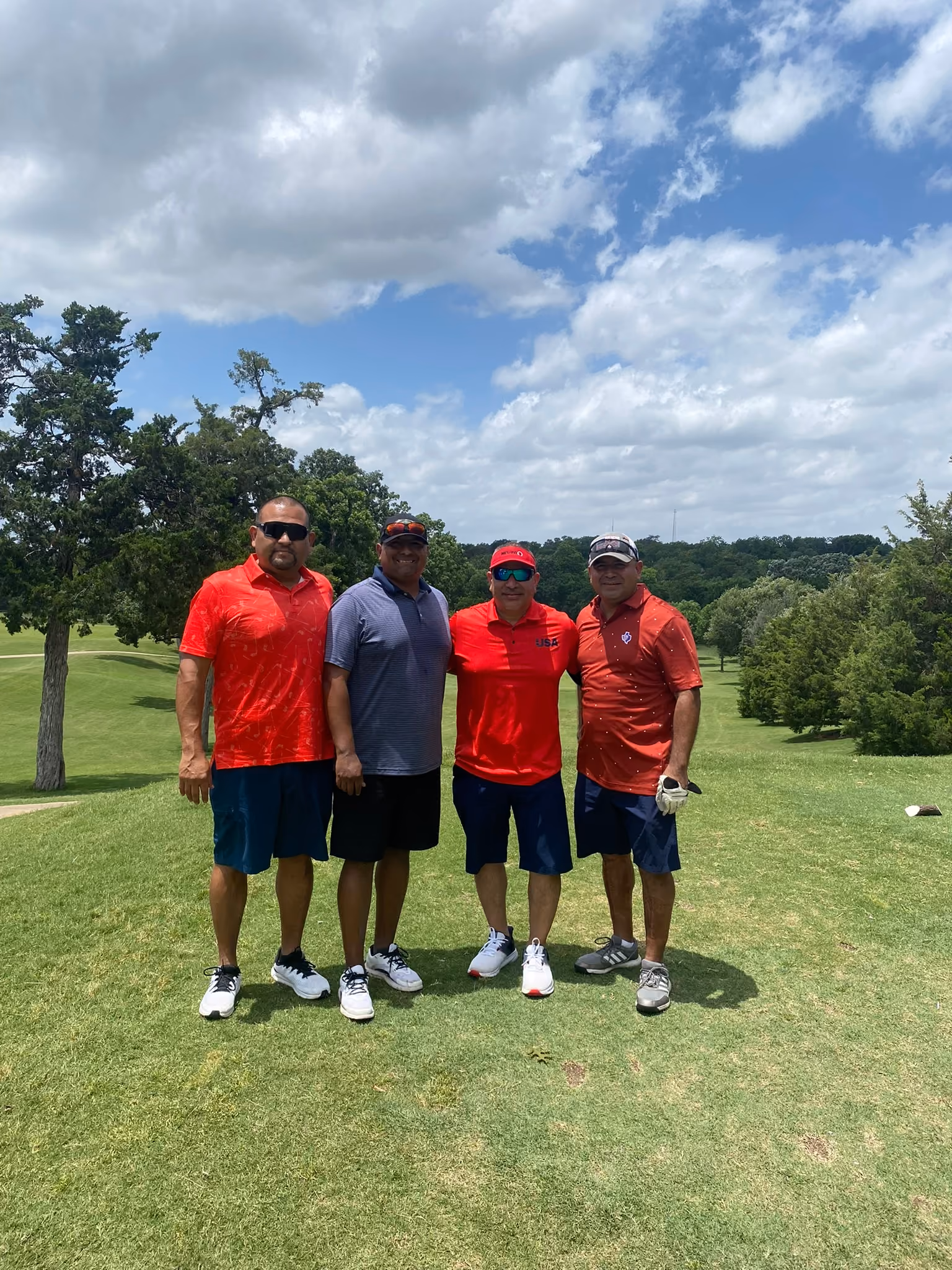 Four golfers posing together on a sunny golf course
