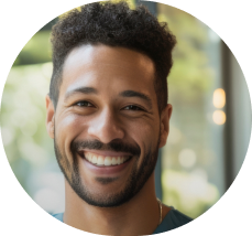 Smiling man with curly hair and beard in a softly lit indoor setting.