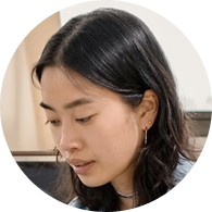 Portrait of a woman with long black hair looking down thoughtfully.