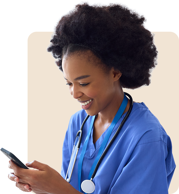 Smiling female healthcare professional in blue scrubs with a stethoscope, looking at a smartphone.