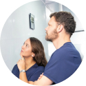 Couple standing close together looking at a mirror.