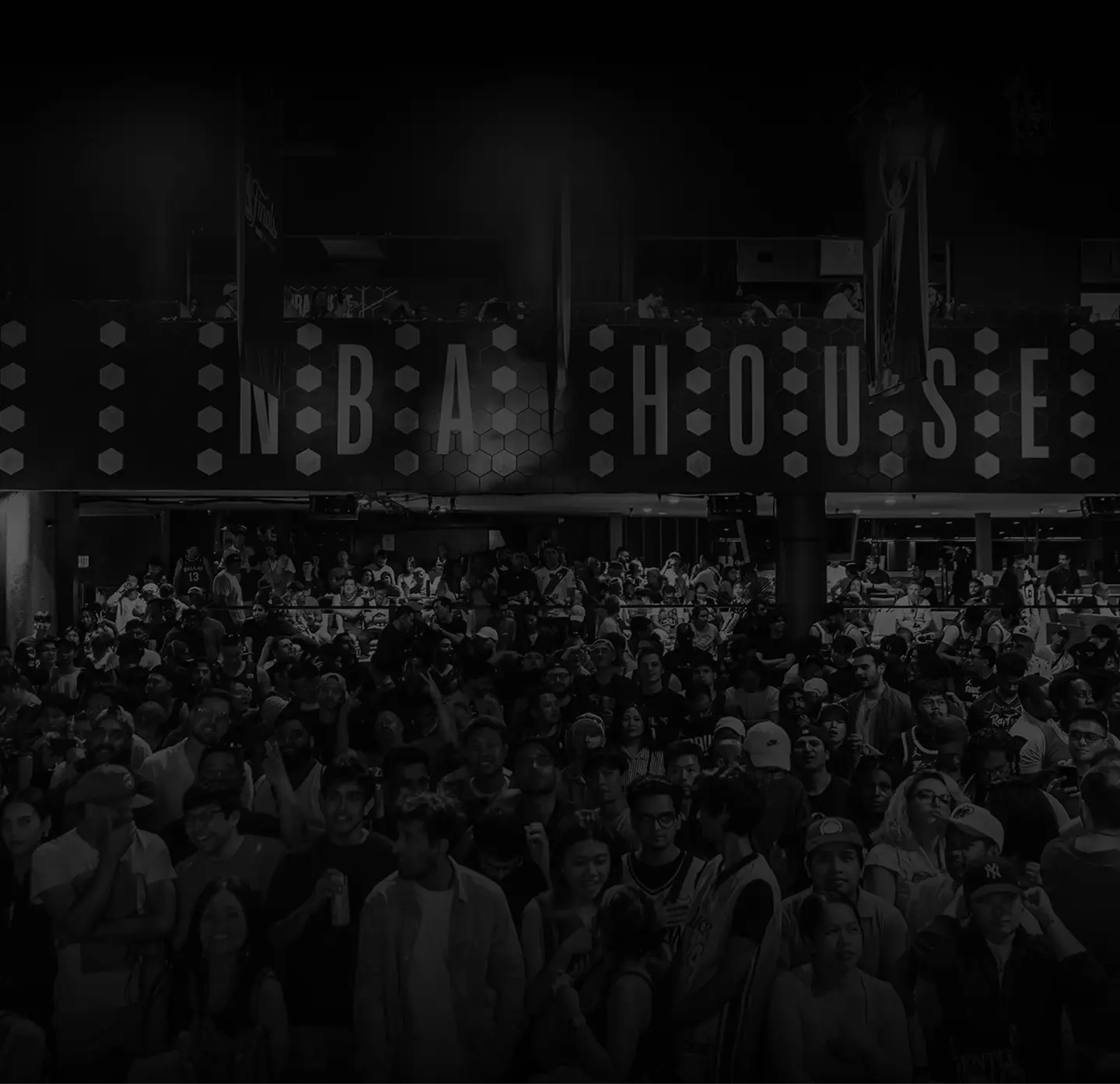 Crowd of people gathered inside an NBA House venue with large signage displaying 'NBA HOUSE'.