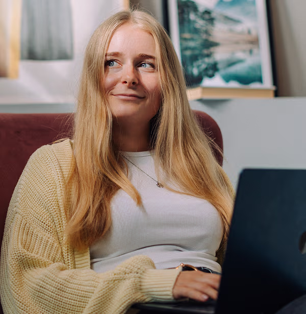 Maja Löwedey, Senior Marketing Manager bei voize, mit gelber Strickjacke und Laptop auf einem Sofa.