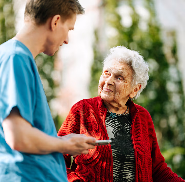 Overhead view of a caregiver playing a board game with residents at a wooden table, smartphone alongside.