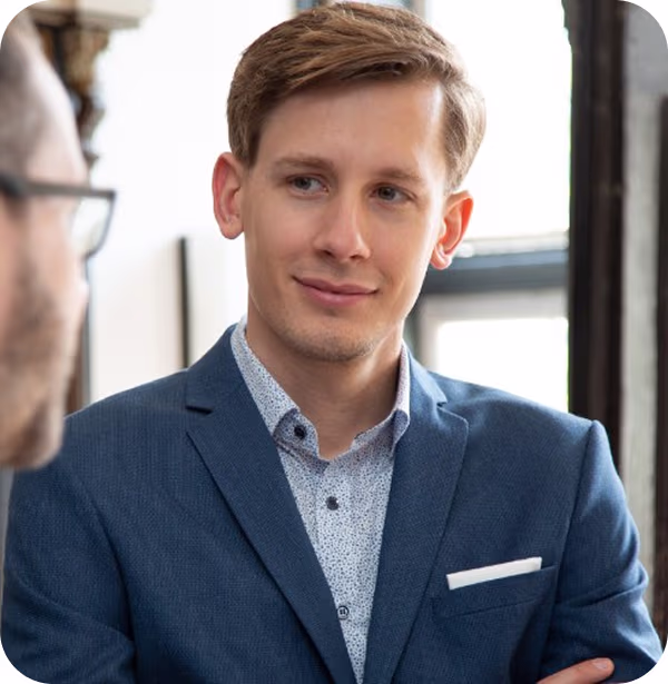 Marc Urban vom Seniorenpark Carpe Diem, lächelnd in blauem Sakko, im Gespräch mit einer Person im Vordergrund.
