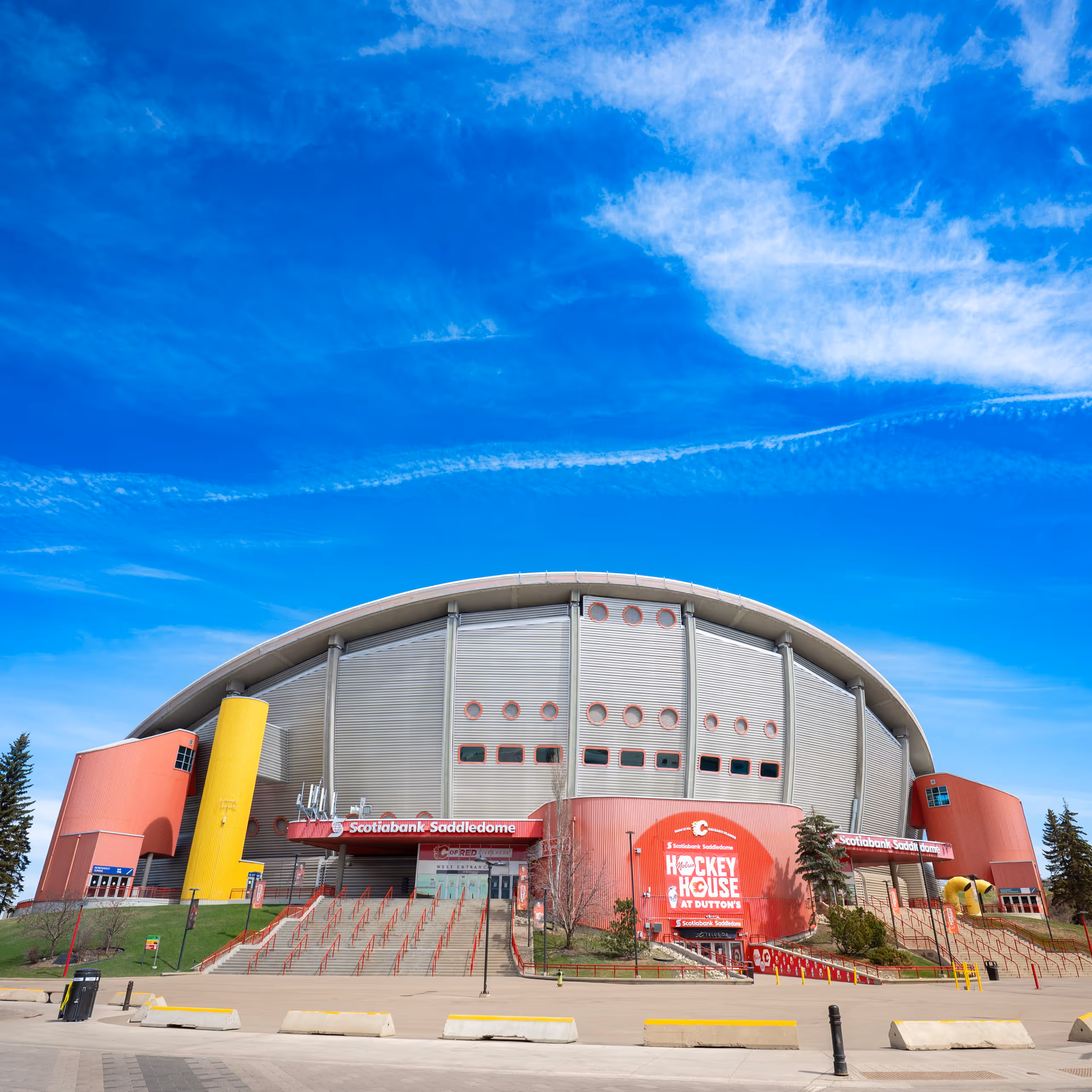Evening view of Scotiabank Saddledome with illuminated Calgary skyline and Calgary Tower in the background.