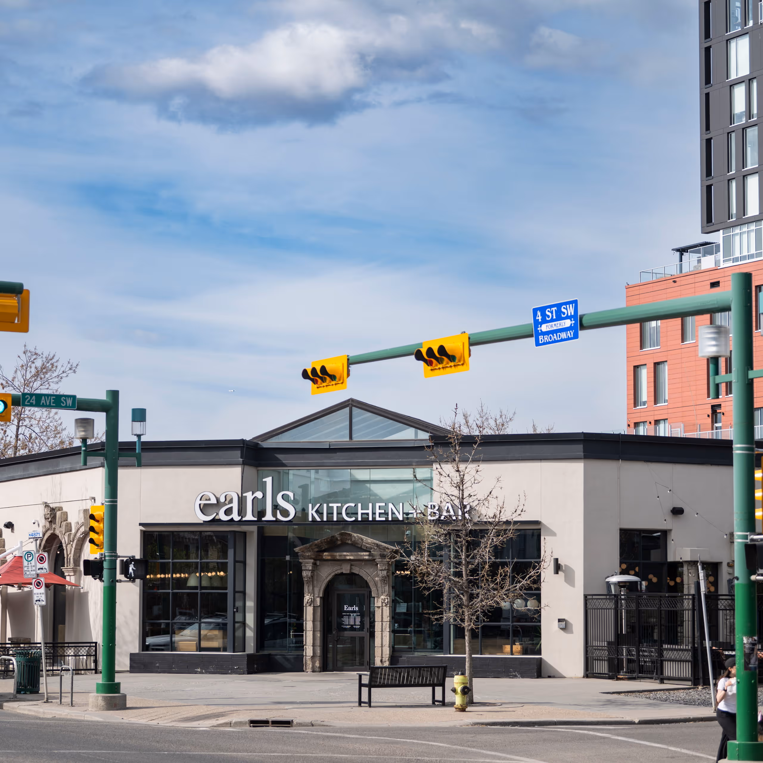Earls Kitchen + Bar building at street corner with traffic lights and bare trees.