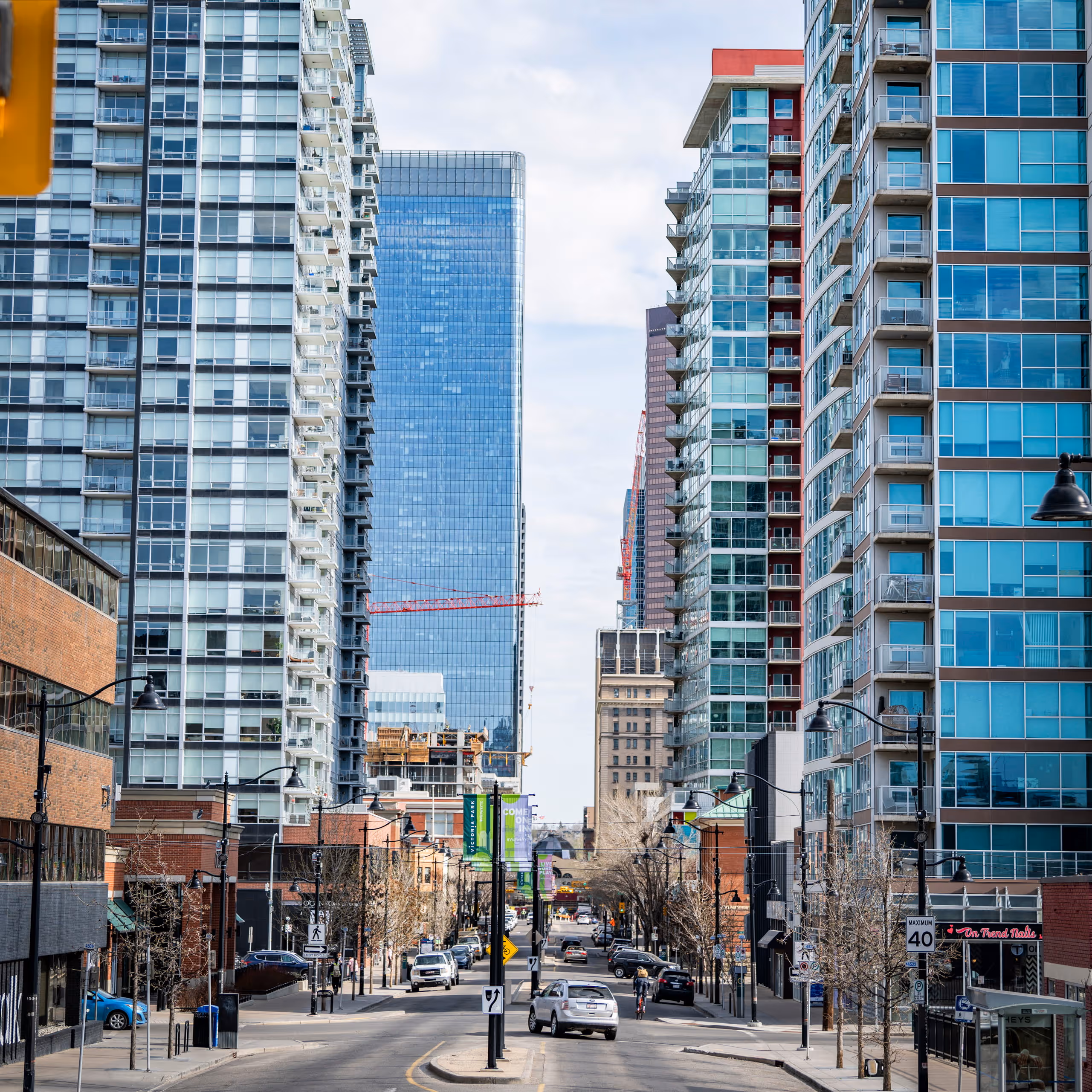 Street view of city with modern high-rise buildings, cars, and a cyclist on the road.