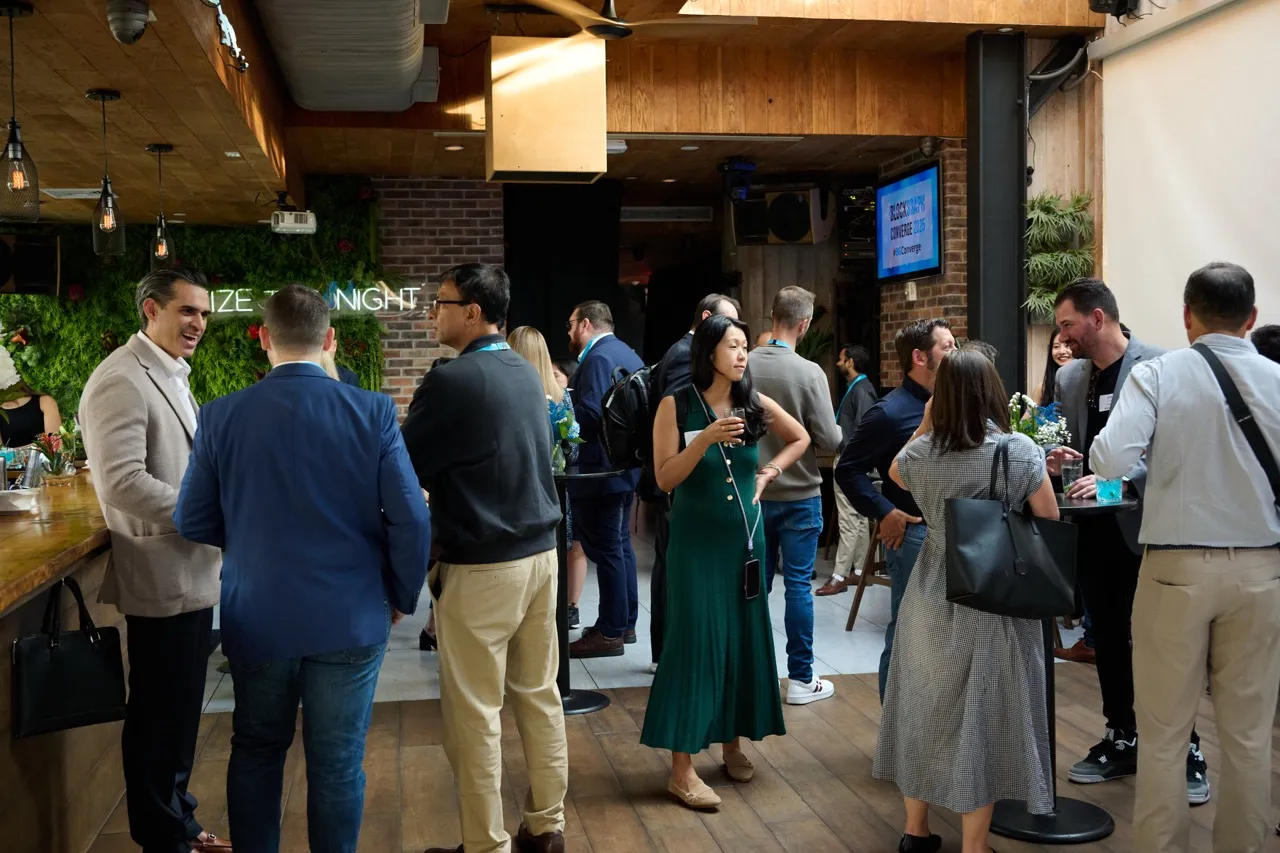 People networking and socializing in a casual indoor event space with wood and brick decor.