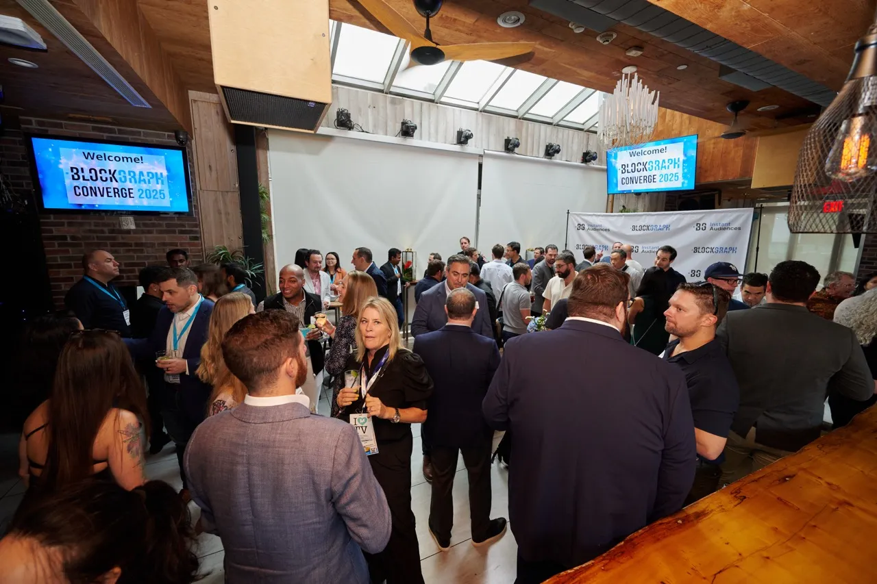 Crowd of people networking and mingling at Blockgraph Converge 2025 event in an indoor venue with welcome screens.
