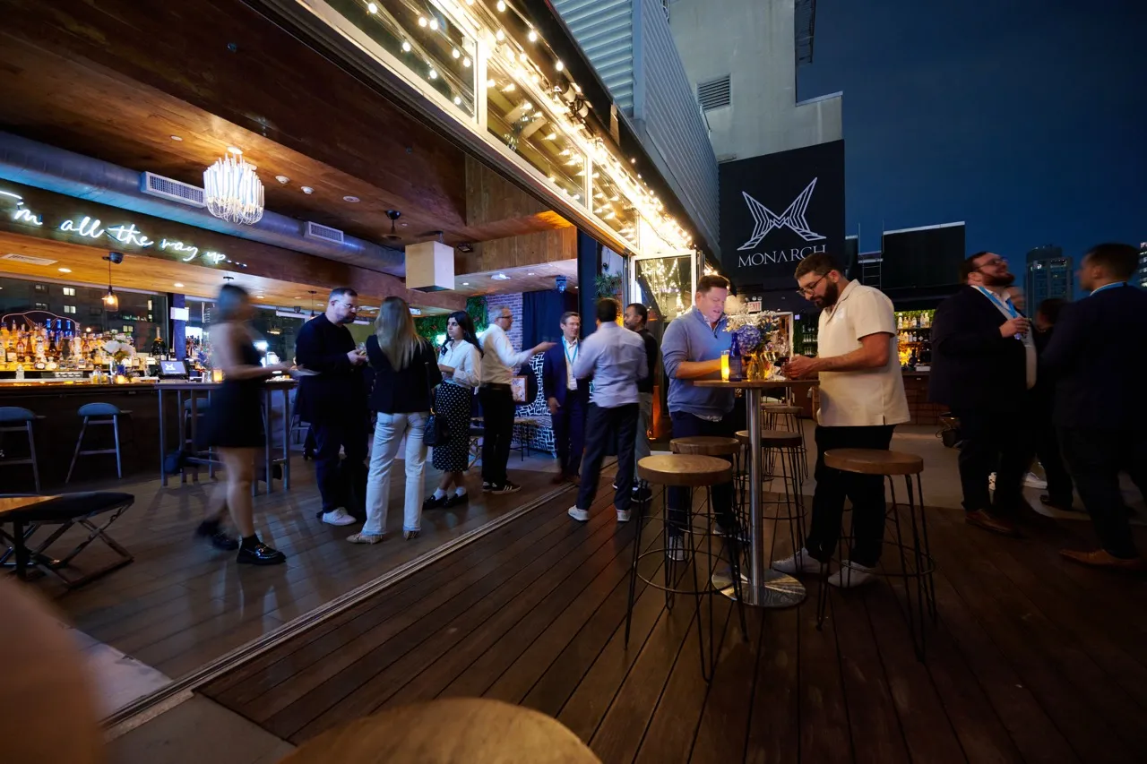 People socializing at an outdoor and indoor bar area in the evening at Monarch venue.