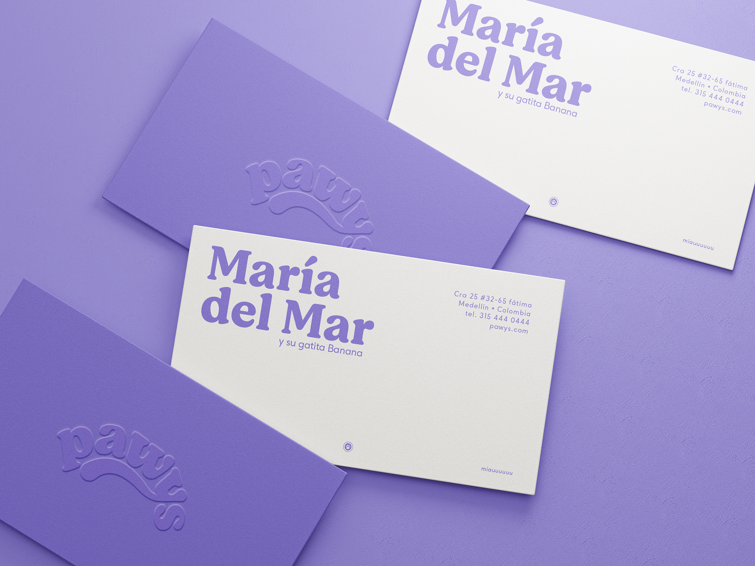 Tarjetas de presentación personalizadas de Pawys con tipografía morada sobre fondo crema y logotipo en relieve sobre fondo morado, con el nombre "María del Mar y su gatita Banana" diseño de papelería y sistema de identidad visual para marca colombiana de productos para mascotas, por Intacto Studio, estudio de branding en Medellín y Bogotá, Colombia.