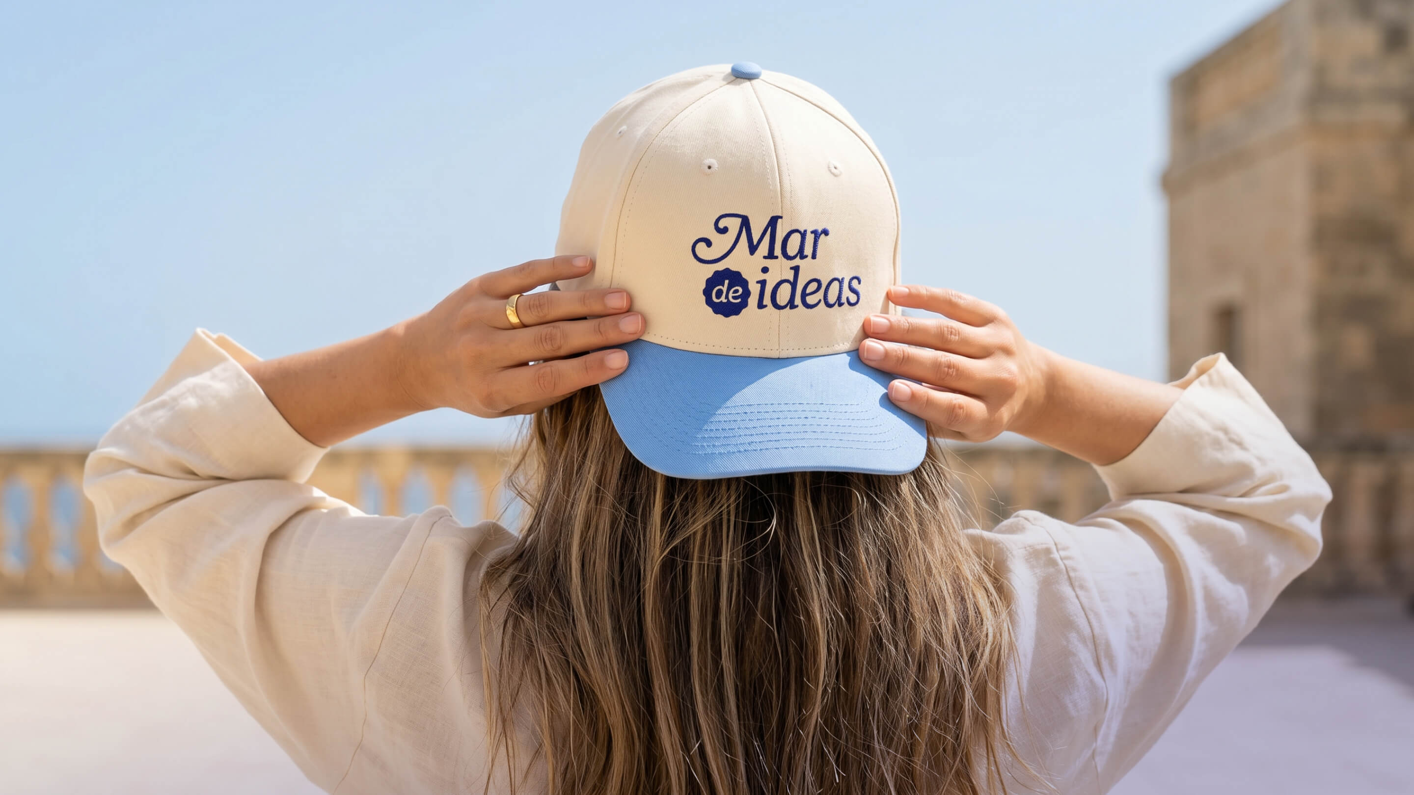 Gorra beige y azul con logotipo bordado de Mar de Ideas, aplicada como pieza de merchandising y extensión de identidad visual para marca personal creada por Intacto Studio.
