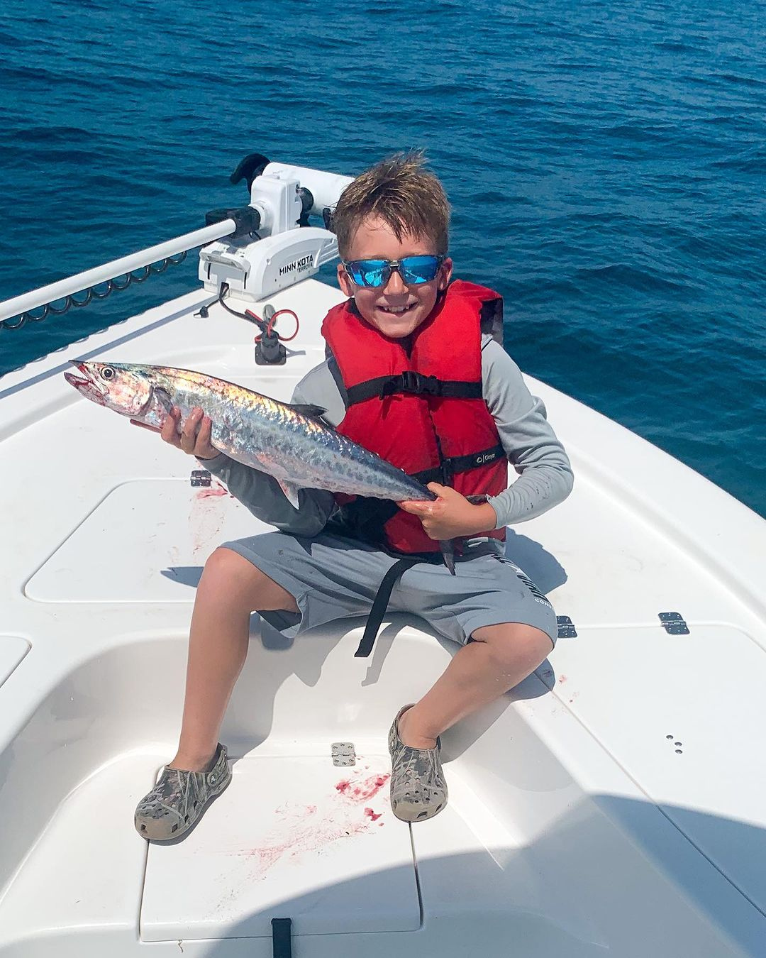 KId with king fish at the front of boat while fishing with reel adventures fishing charter