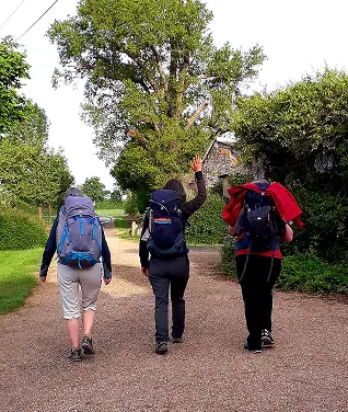 3 personnes de dos qui marchent avec des sac à dos et bâtons de randonnée