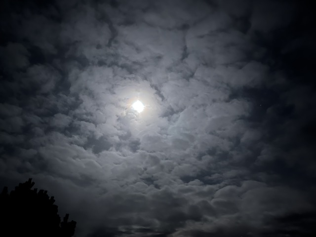 Dunkler Nachthimmel mit Vollmond der durch Wolken durchscheint.