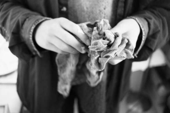 Person holding and twisting a crumpled cloth with both hands in a black and white photo.
