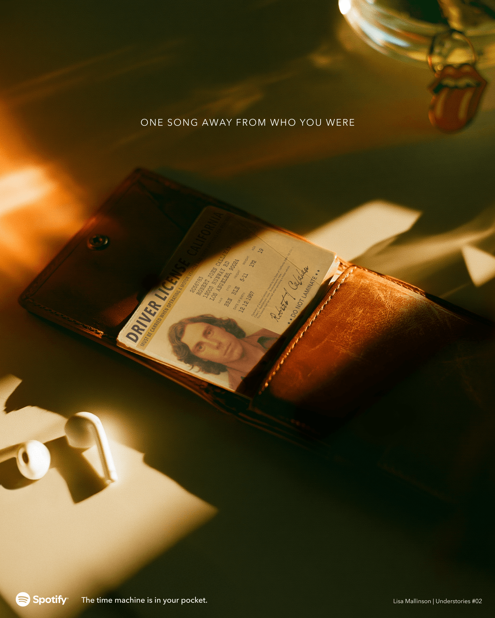 Spotify concept poster showing a vintage California driver’s licence tucked inside a brown leather wallet, with wired earphones nearby in warm sunlight. Text reads: “One song away from who you were” and “The time machine is in your pocket.”